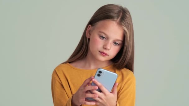 Uma Menina Sorrindo Usando Seu Móvel Isolado Sobre Uma Parede — Vídeo de Stock