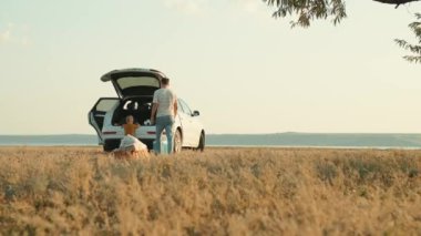 Baba ve oğlunun, doğada arabanın bagajından futbol topunu almaları.