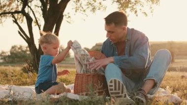 Baba ve oğlunun piknik sepetinden bir şeyler çıkardığı yakın çekim görüntüsü.