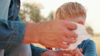 Piknikte şekerden sonra oğlunun ellerini silen bir babanın yakın çekim görüntüsü.