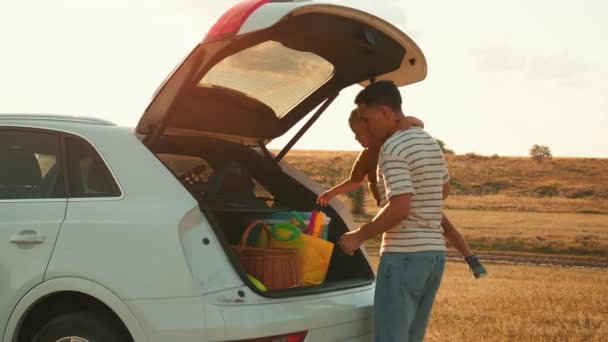 Vader Met Zoon Armen Haalt Dingen Uit Kofferbak — Stockvideo