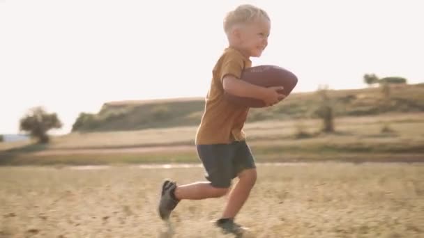 英俊的微笑的父亲抓住了他的儿子 他带着一个球在大自然中奔跑 — 图库视频影像