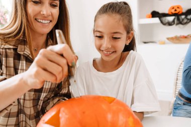 Beyaz anne ve kız Cadılar Bayramı 'nı evde birlikte geçirirken gülümsüyorlar.