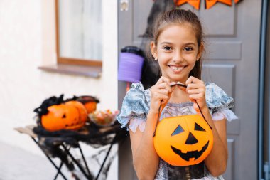Beyaz kız Cadılar Bayramı 'nda dışarıda şaka mı şeker mi oynarken gülüyor.