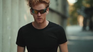 Kameraya doğru koşan güneş gözlüklü konsantre bir sporcunun yakın çekim görüntüsü.