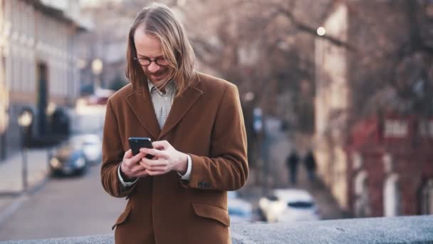 Uomo Positivo Dai Capelli Lunghi Cappotto Nastro Fogliare Sul Telefono — Video Stock