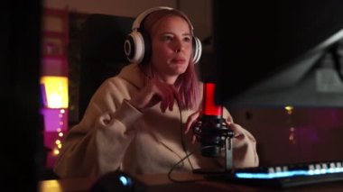 Profesyonel bir oyuncu kız bir oyun yayınlıyor ve mikrofona konuşuyor.