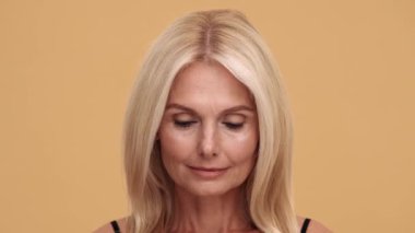 Bej stüdyodaki kameraya bakan konsantre olmuş güzel bir kadının yakından görüntüsü.
