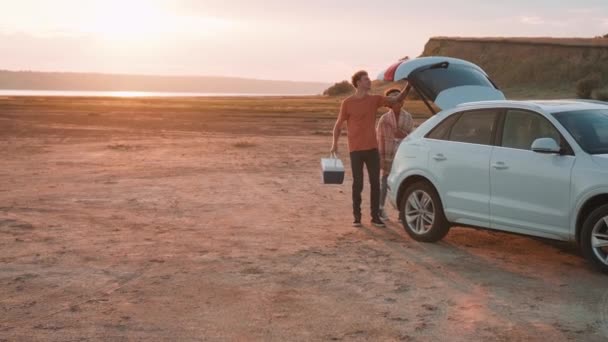 Hermosa Pareja Multinacional Sacando Una Cesta Picnic Del Maletero Coche — Vídeos de Stock