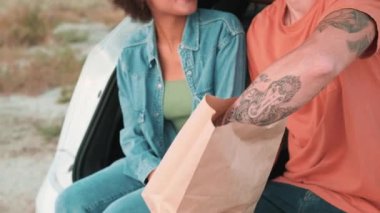 Doğada bir arabanın bagajında sevgilisine elma veren mutlu adamın yakın plan görüntüsü.