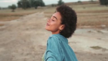 Olumlu, yakışıklı Afrikalı kadının haliçlerin arasında dururken derin bir nefes alışının yan görüntüsü.