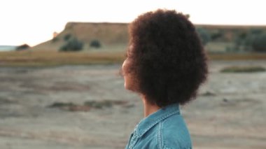 Olumlu Afrikalı kadının nehir kıyısında dikilip etrafa bakınışının yan görüntüsü.