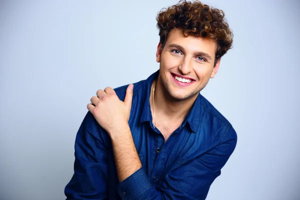 Beau homme aux cheveux bouclés sur fond bleu — Photo