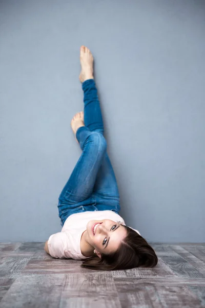 Woman lying on the floor with legs raised up — Stock Photo, Image