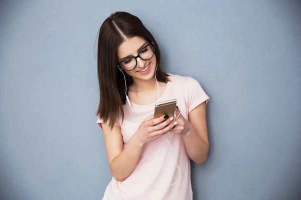 Vrouw met behulp van smartphone met koptelefoon — Stockfoto