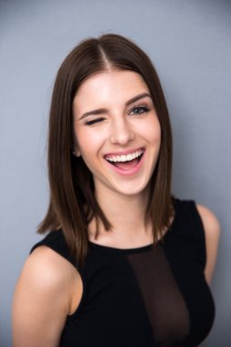 Mutlu kadın gri arka plan üzerinde göz kırpıyor