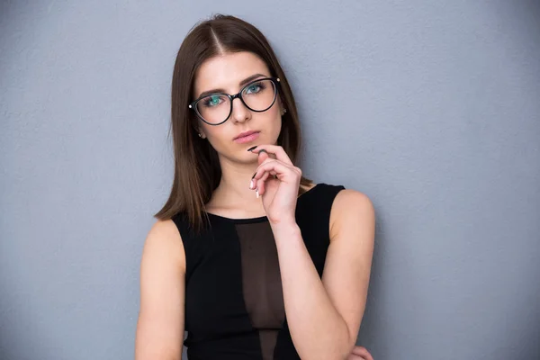 Leuke doordachte vrouw permanent over grijze achtergrond — Stockfoto