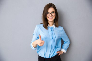 İşkadını başparmak ile gri arka plan üzerinde gülümseyen