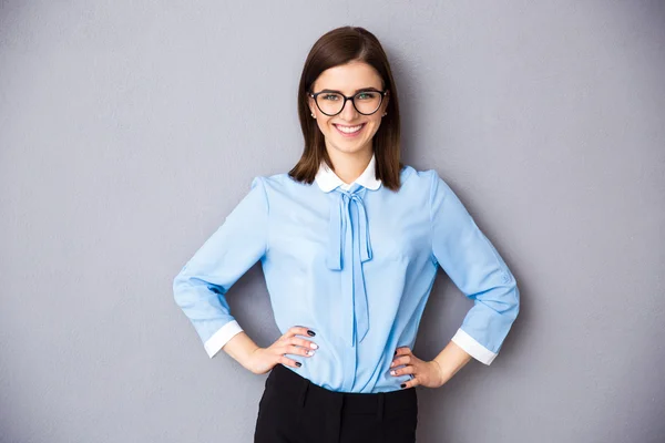Mujer de negocios sonriente en gafas sobre fondo gris —  Fotos de Stock