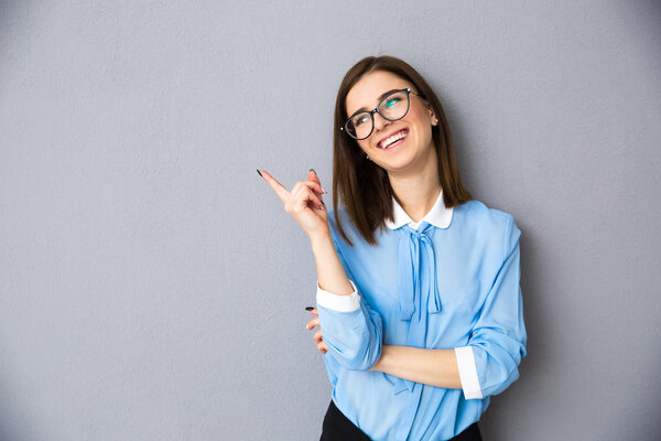 Cheerful businesswoman in glasses pointing away