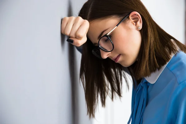 Deprimerad affärskvinna lutar på grå väggen — Stockfoto