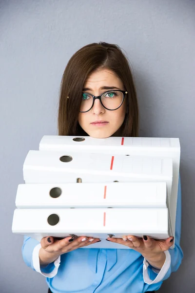 Tired young businesswoman standing with folders — Stock Photo, Image