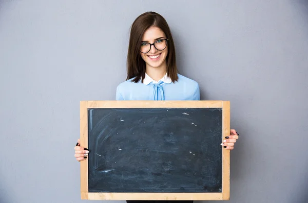 Lachende vrouw permanent met billboard over grijze achtergrond — Stockfoto