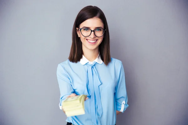 Smiling businesswoman giving money on camera — Stock Photo, Image