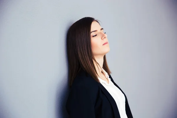 Mujer de negocios cansada apoyada en la pared gris —  Fotos de Stock