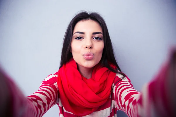 Beautiful woman kissing at camera over gray background — Stock Photo, Image