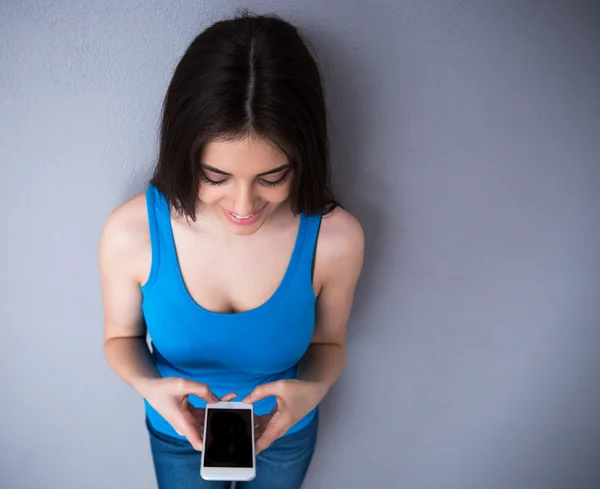 Mujer feliz usando teléfono inteligente sobre fondo gris — Foto de Stock