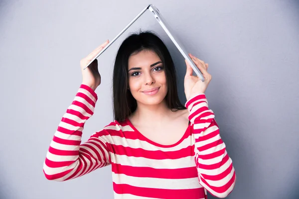 Woman holding a laptop above her head like a roof — Stock Photo, Image