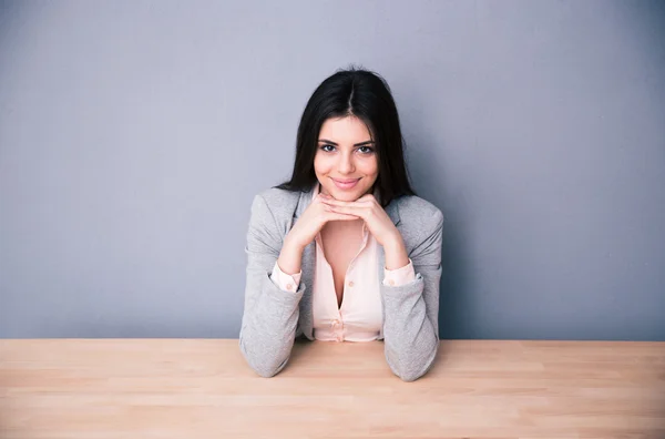 Glückliche junge Frau sitzt am Tisch — Stockfoto