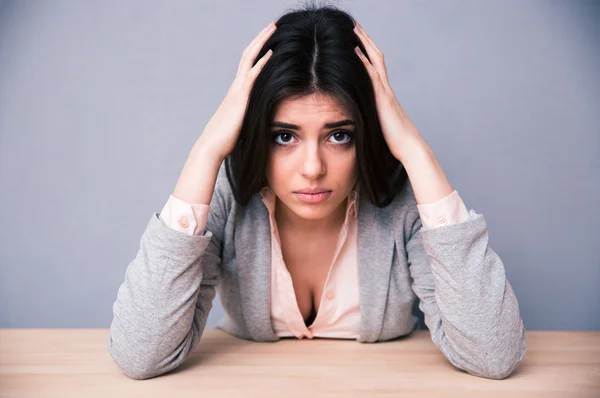 Belle femme sérieuse assise à la table — Photo