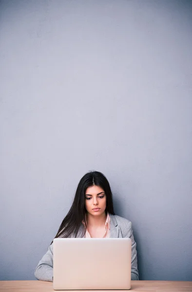 Mujer linda joven sentado en la mesa con el ordenador portátil — Foto de Stock