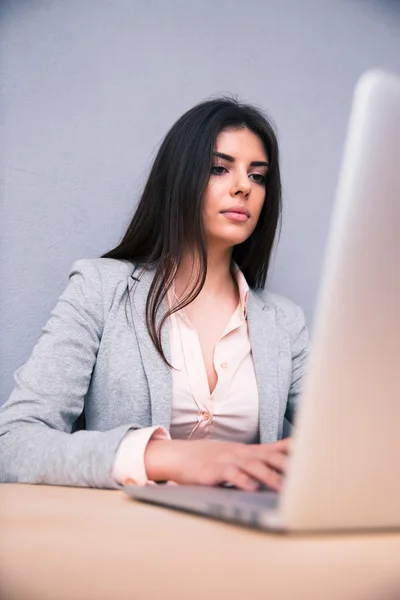 Mujer joven sentada en la mesa y usando el portátil —  Fotos de Stock