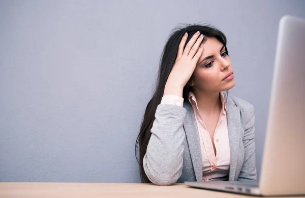 Mulher atraente sentada na mesa com laptop — Fotografia de Stock