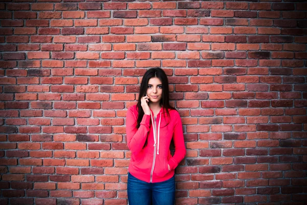 Belle femme parlant au téléphone sur un mur de briques — Photo