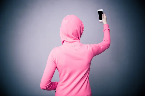 Een back-weergave portret van een vrouw met smartphone — Stockfoto