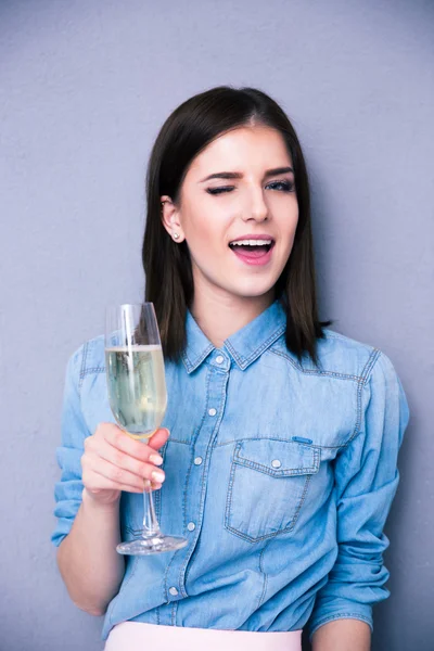 Woman holding glass of champagne and winking — Stock Photo, Image