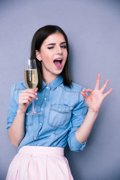 Vrouw houden glas champagne en tonen ok gebaar — Stockfoto