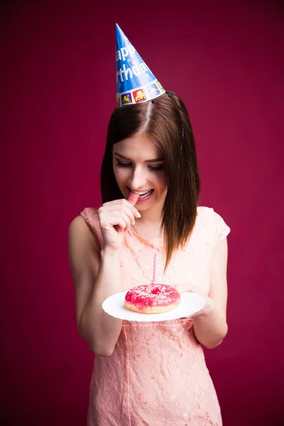 Pensive young woman holding donut with candle — Stock Photo, Image