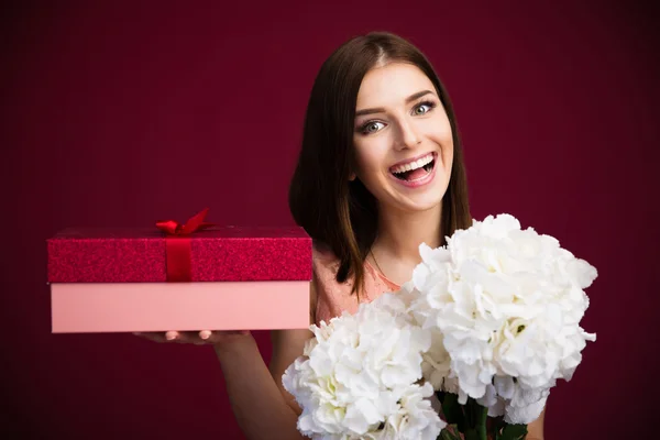 Lächelnde süße Frau mit Geschenkbox und Blumen — Stockfoto