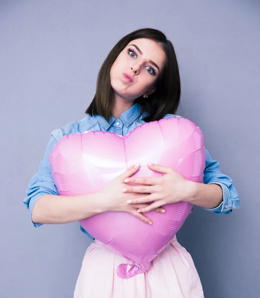 Ofendida joven sosteniendo globo en forma de corazón —  Fotos de Stock