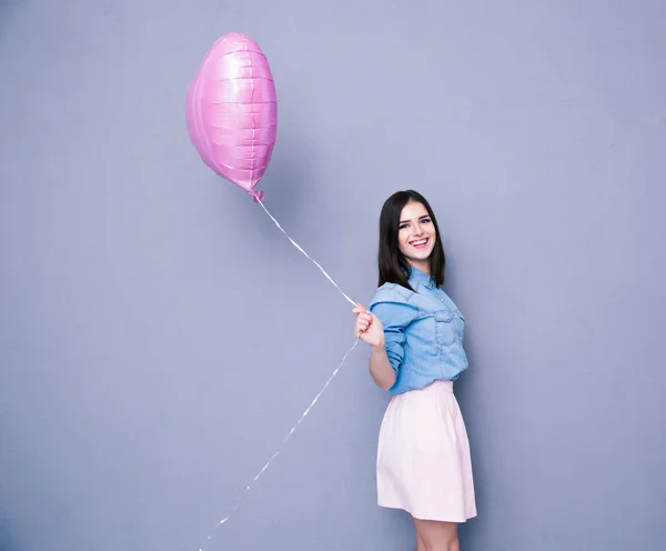 Veselá žena drží balón a při pohledu na fotoaparát — Stock fotografie