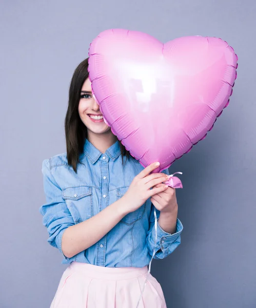Усміхнена жінка прикриває око повітряною кулею у формі серця — стокове фото