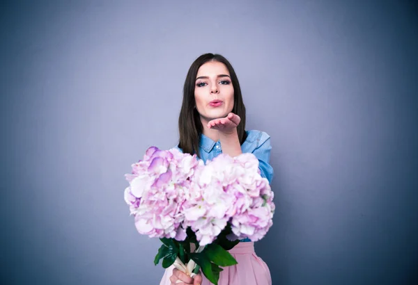 Hermosa mujer sosteniendo flores y enviando beso — Foto de Stock