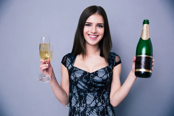 Mujer sonriente sosteniendo dos copas y una botella de champán —  Fotos de Stock