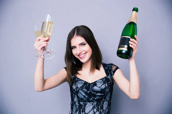 Mujer sonriente sosteniendo dos copas y una botella de champán —  Fotos de Stock