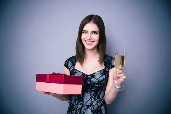 Happy woman holding glass of champagne and gift box — Stock Photo, Image